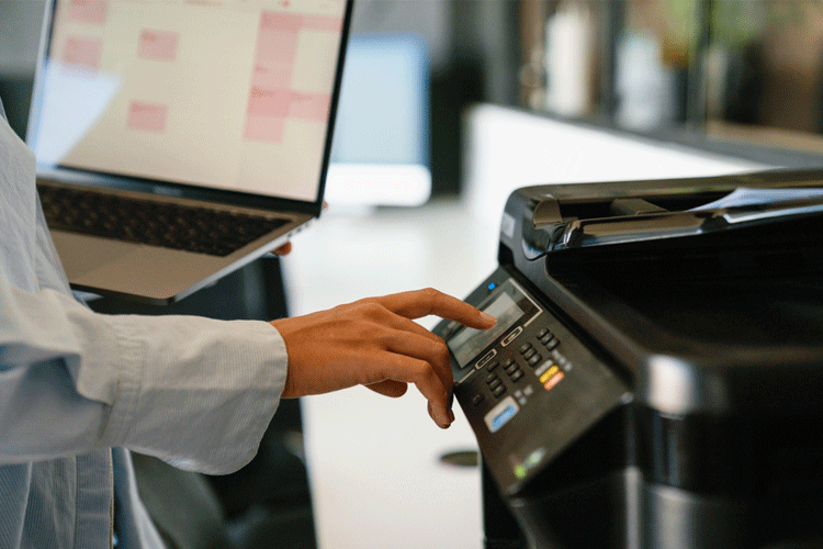 Eine Hand bedient einen modernen Drucker – das Bild symbolisiert professionelles IT-Drucker-Management, das für reibungslose Abläufe, effiziente Wartung und optimale Verfügbarkeit von Druckressourcen sorgt